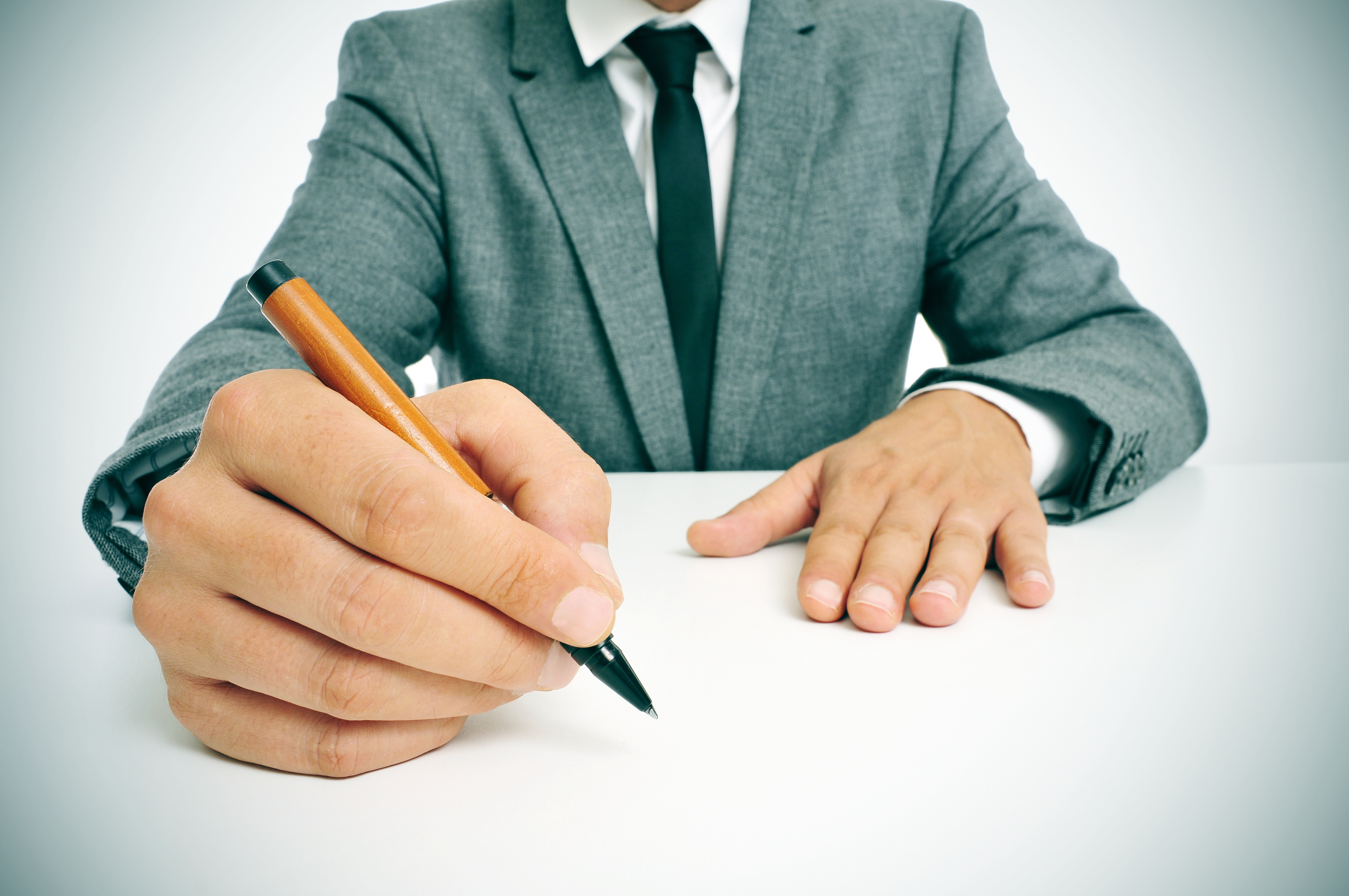 man in suit with a pen in his hand ready to write